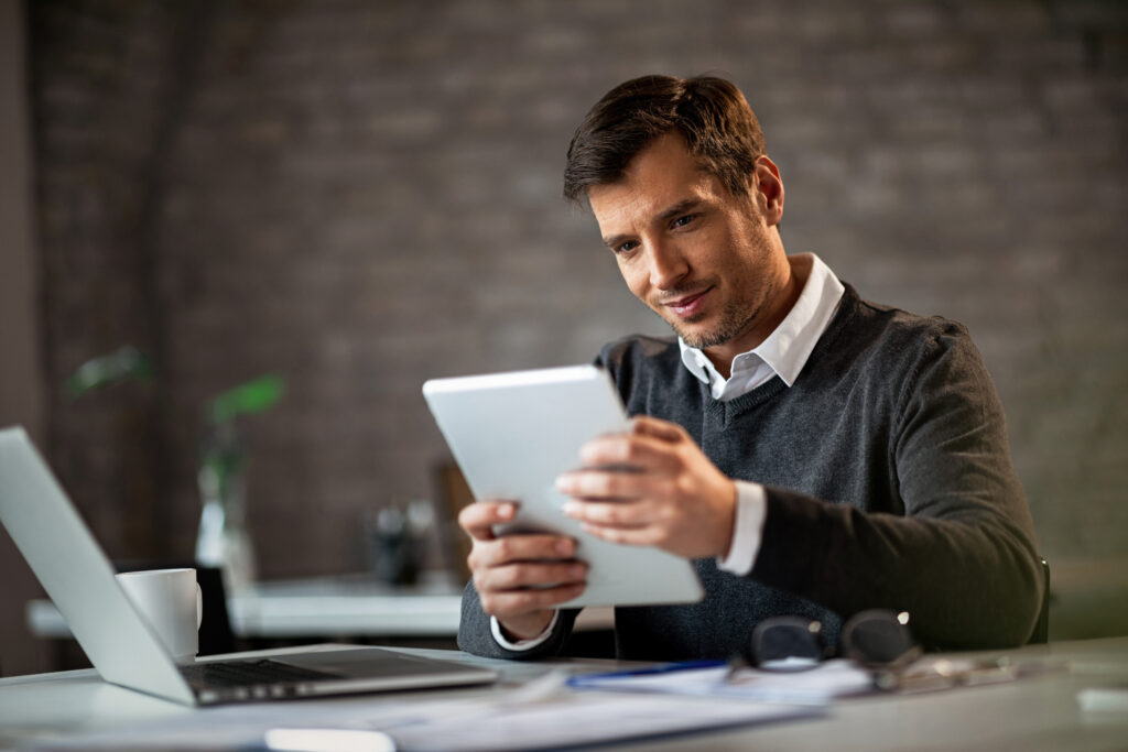 Happy businessman working on touchpad while being in the office.